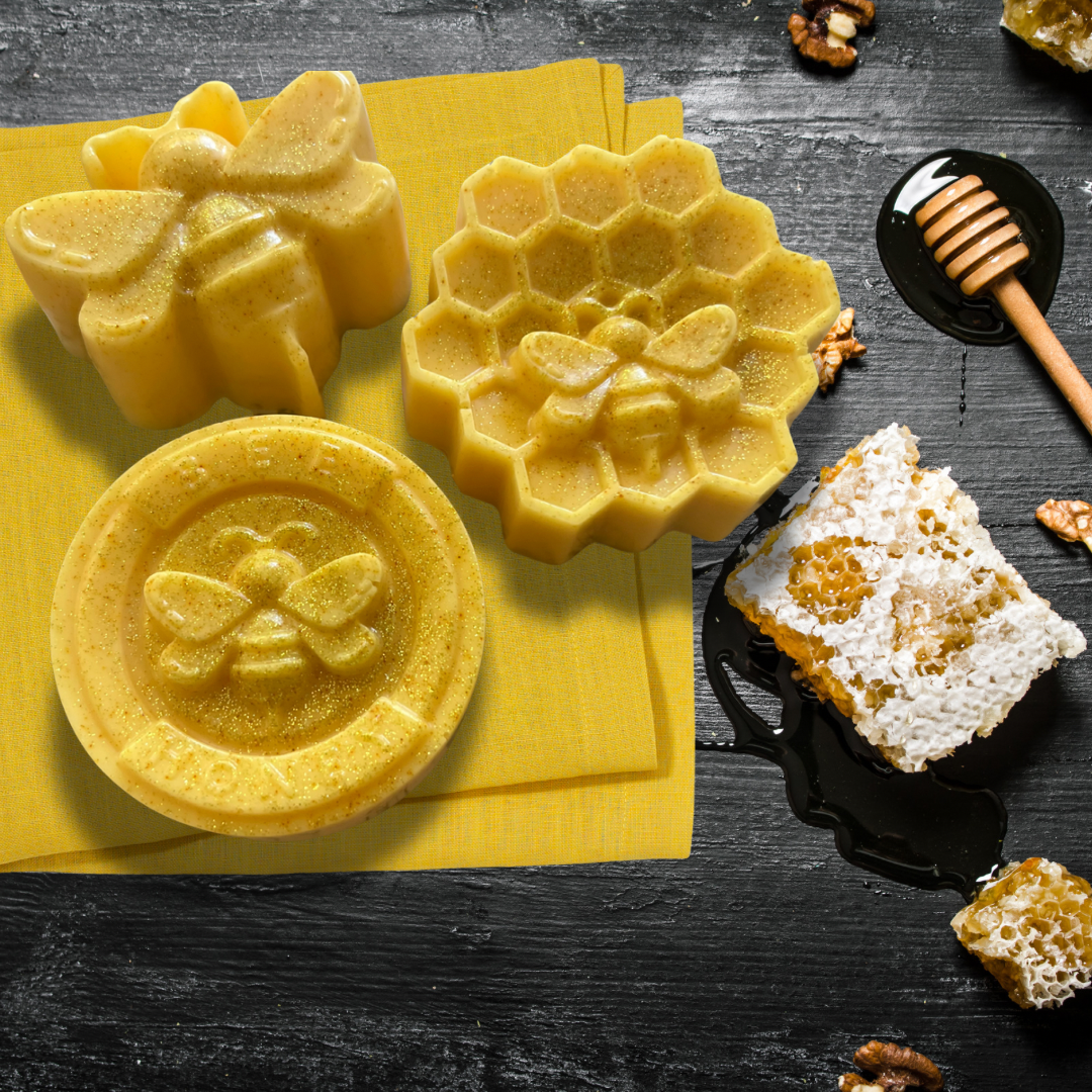 Bee themed soap products on a dark surface with honeycomb and honey.