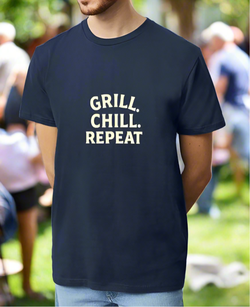 Person wearing a navy blue t-shirt with 'GRILL. CHILL. REPEAT' text in a park setting.