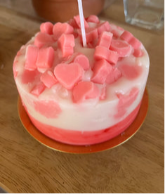 Pink and white cake with heart-shaped decorations on a wooden surface