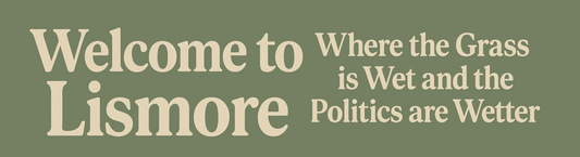 Text 'Welcome to Lismore Where the Grass is Wet and the Politics are Wetter' on a green background