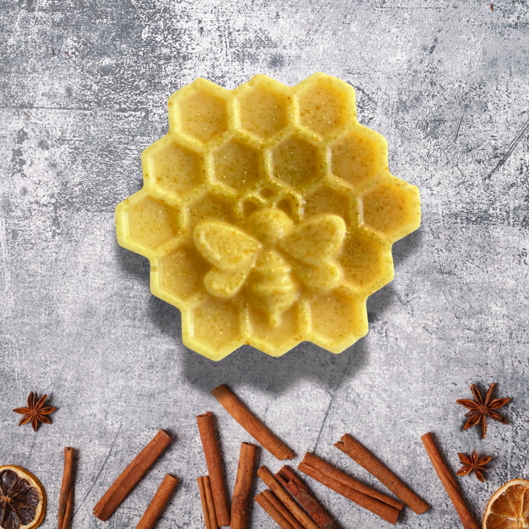 Yellow honeycomb-shaped wax melt on a gray surface with cinnamon sticks and star anise.