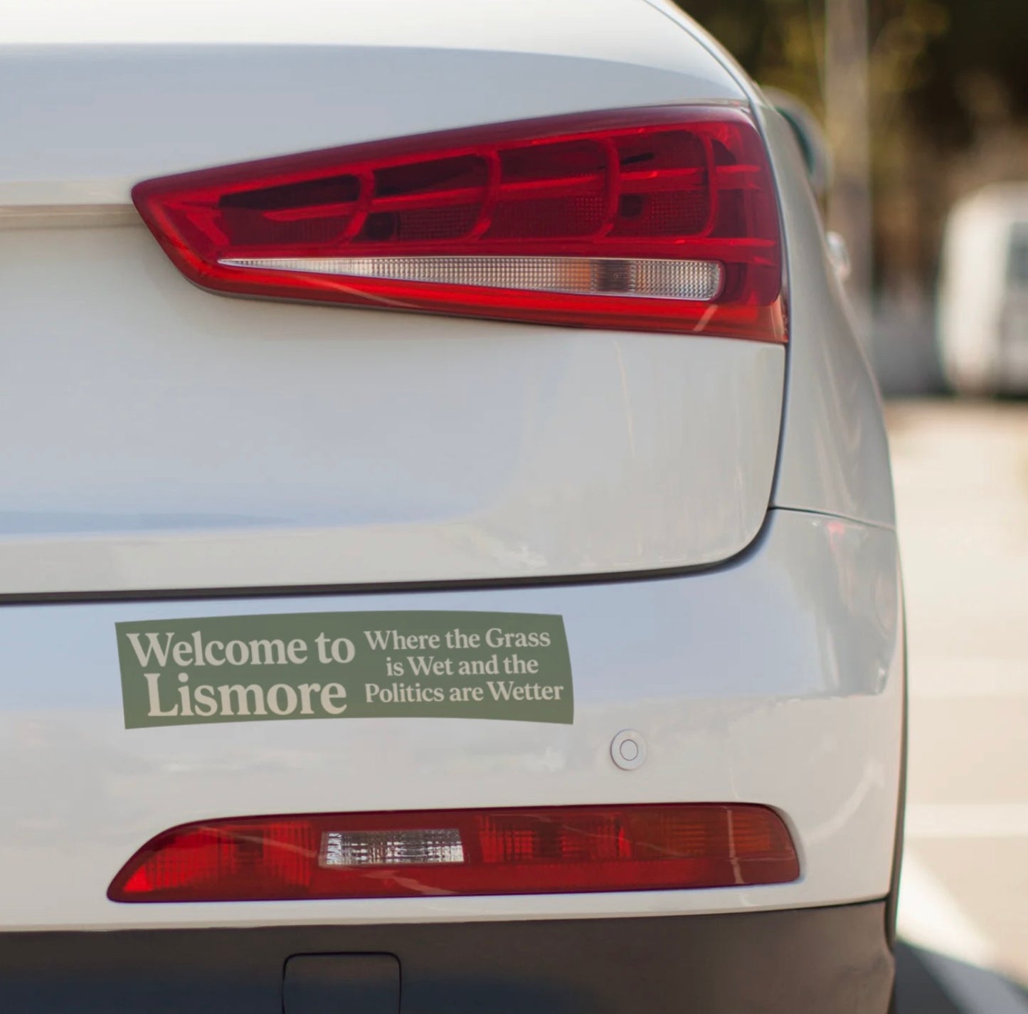 Car tail light with a humorous bumper sticker on a blurred background