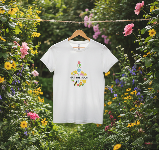 White t-shirt with a colorful graphic and text 'EAT THE RICH' on a hanger surrounded by flowers.