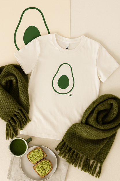 White t-shirt with avocado graphic, green scarf, and avocado toast on a light surface