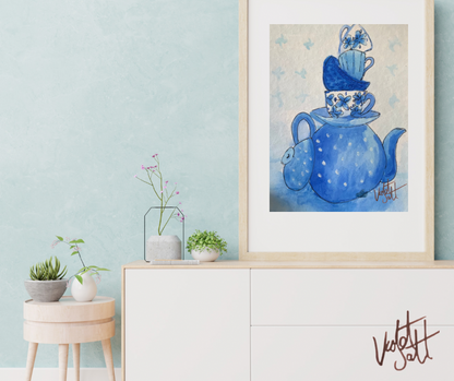 Framed artwork of a blue teapot and cups on a white dresser with light blue wall.