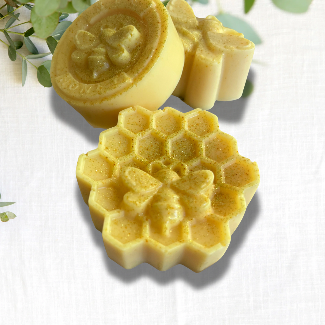 Three yellow honeycomb-shaped soap bars on a white background with green leaves.