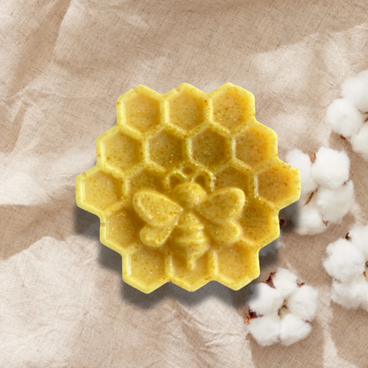 Yellow honeycomb-shaped soap on a beige fabric background with cotton fibers.