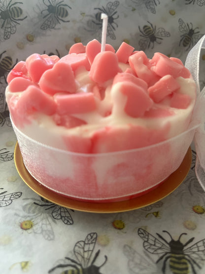 Pink and white candle with a wick on a patterned surface