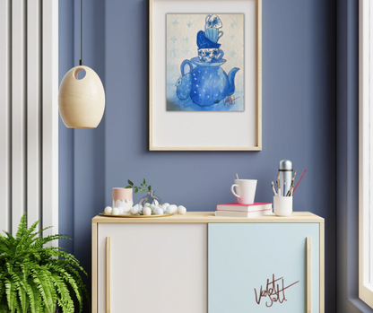 Framed artwork of a blue teapot on a blue wall above a cabinet with decorative items.